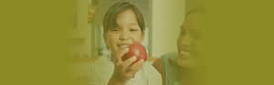 Young child smiling holding an apple